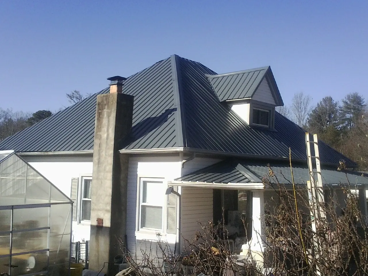 Dark blue standing seam metal roof on a white farmhouse with dormer — Slate & Tile Roof Repair by Roofing Brothers in Lynn