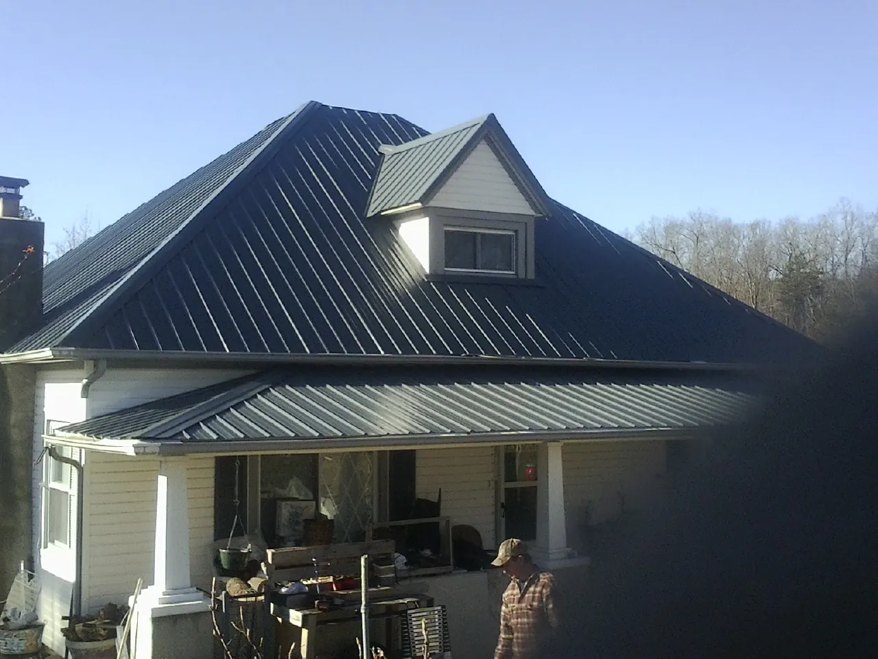 Dark blue standing seam metal roof with a dormer above a front porch in Lynn