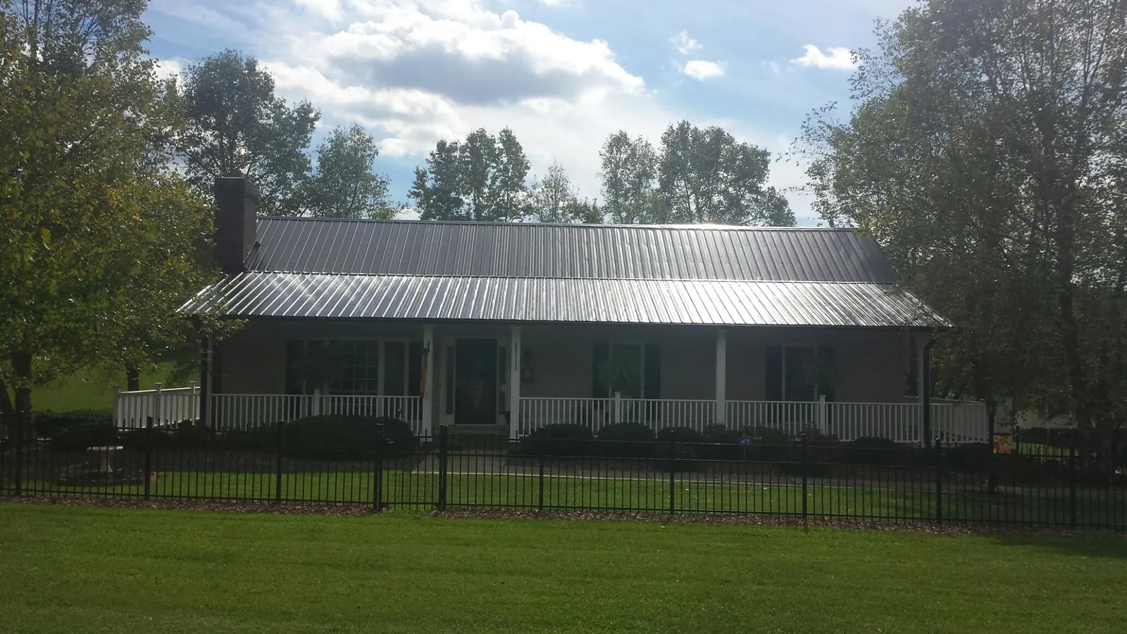 Gray metal roof on a brick ranch with a full width front porch — Gutter Guard Installation work by our crew in Lynn