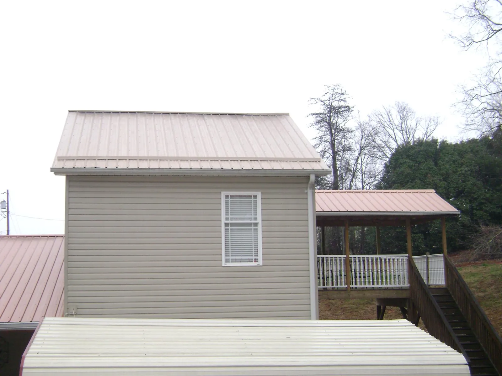 Tan metal roofs on a two story addition and attached porch, from a Roof Replacement job in Lynn